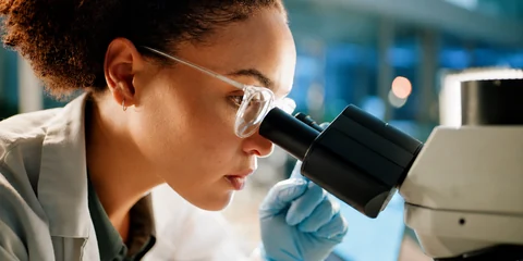 Une chercheuse au microscope dans un laboratoire d'analyse